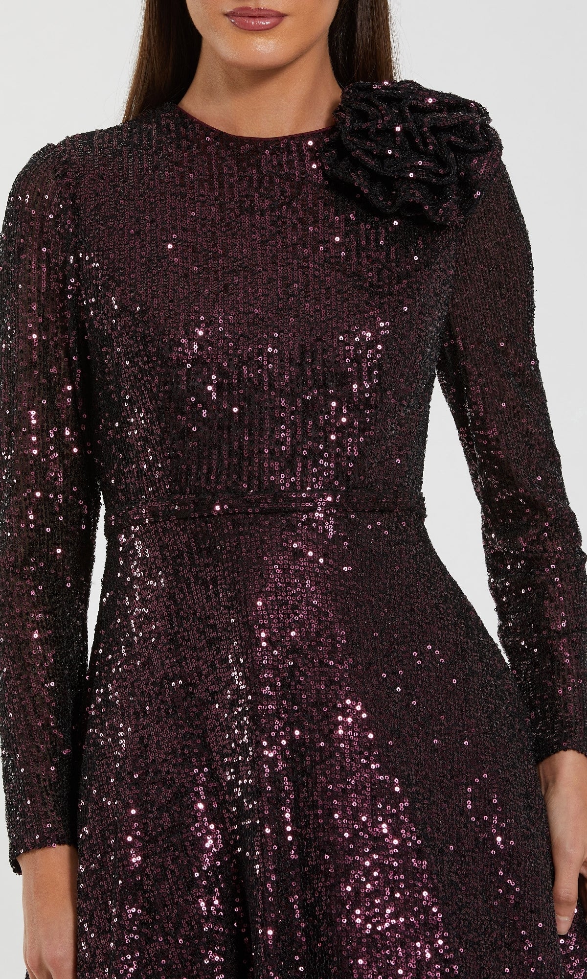 A woman wears the Mac Duggal 56178 Amethyst Sequin Formal Dress, featuring long sleeves and a statement flower on the left shoulder—an elegant option for any mother of the bride.